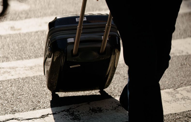 Traveller pulling a wheeled suitcase across a street