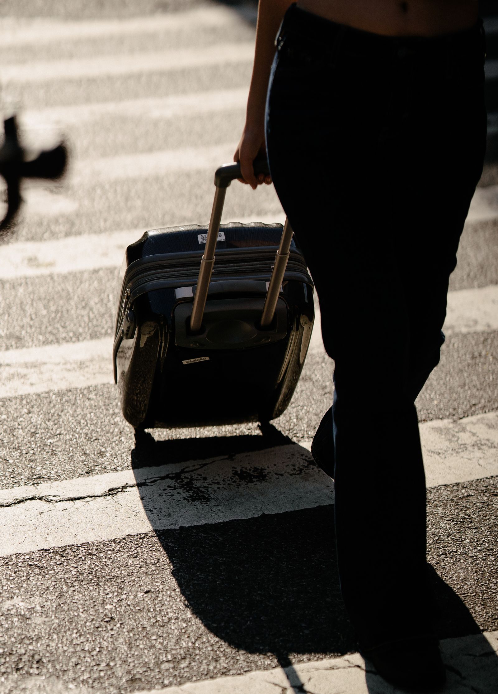 Traveller pulling a wheeled suitcase across a street