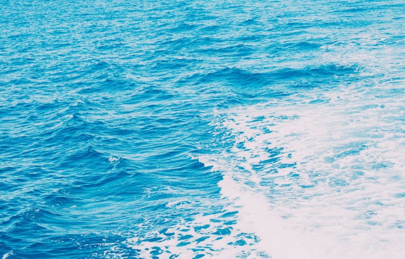 White ship wake across blue ocean water