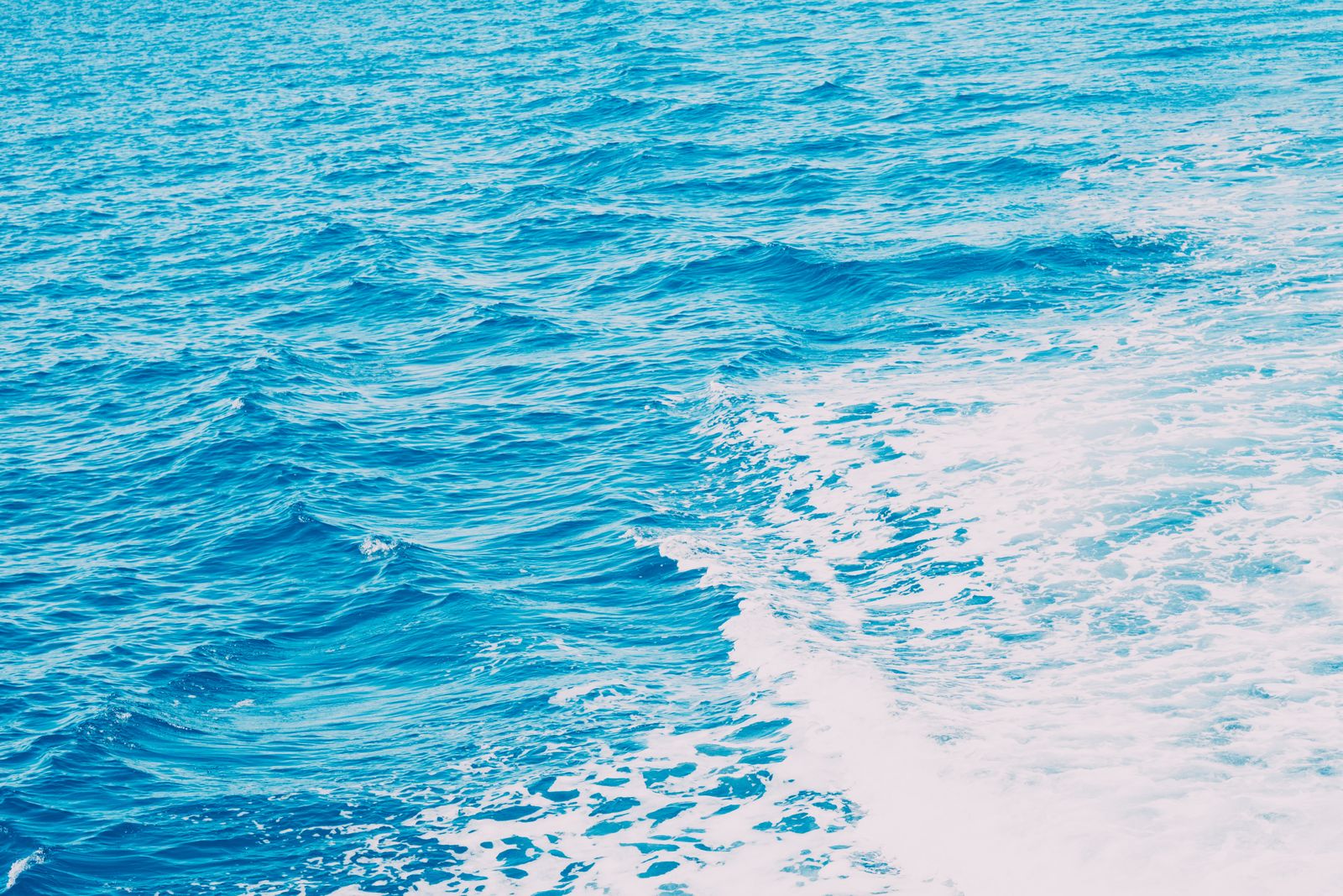 White ship wake across blue ocean water